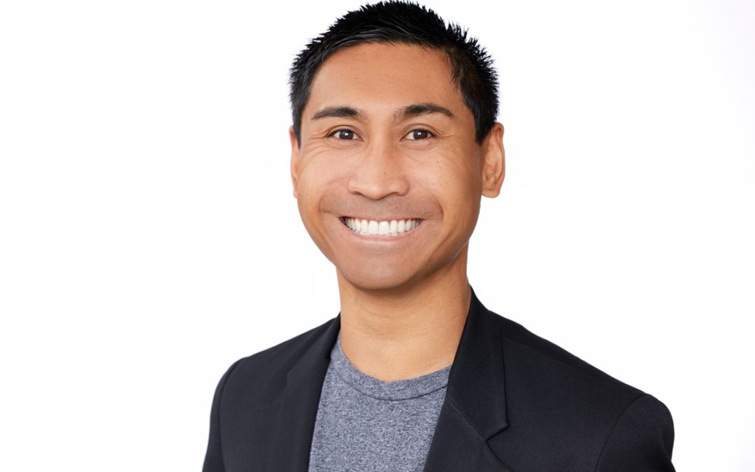 headshot of Jessper Maquindang, wearing a dark gray jacket, gray shirt, and big smile