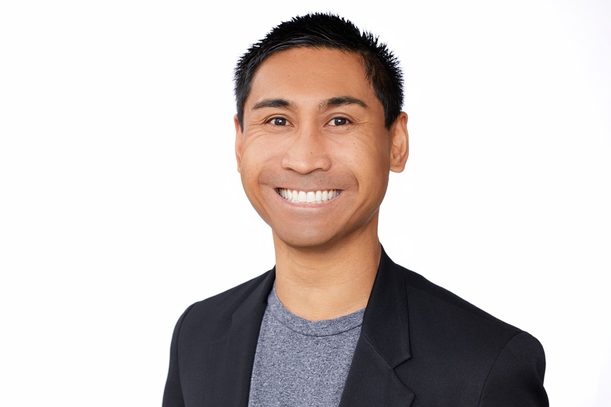 headshot of Jessper Maquindang, wearing a dark gray jacket, gray shirt, and big smile