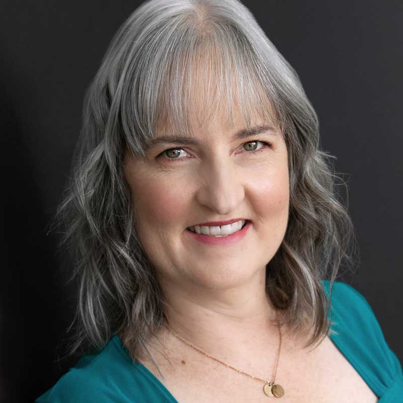Headshot of Candy Messer, with long gray hair and green top