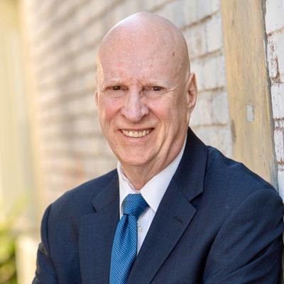 Headshot of Gary Howarth - male wearing blue suit and blue tie smiling