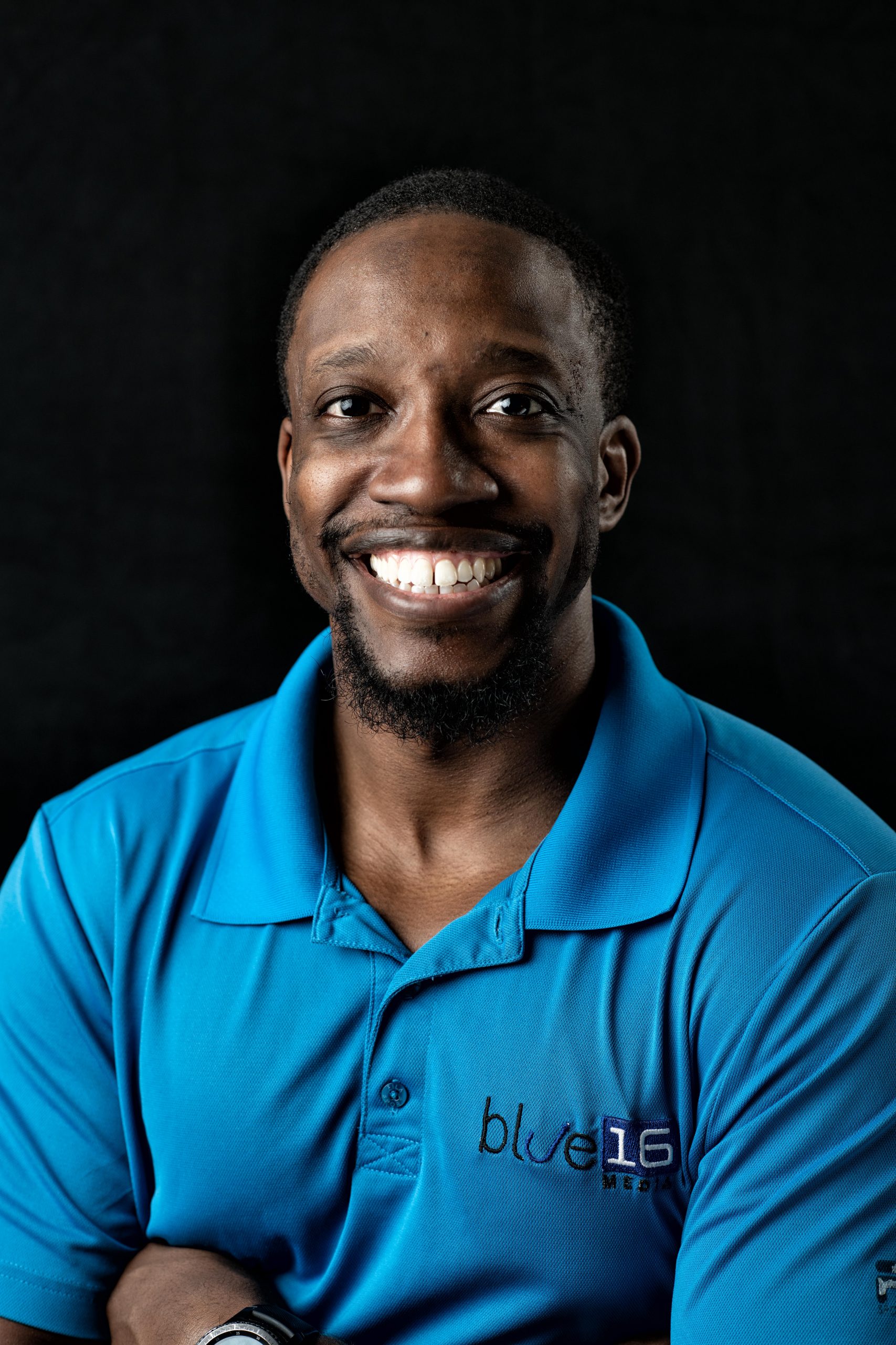 Headshot of Gresham Harkless Jr. - man smiling wearing blue shirt with logo Blue 16 Media