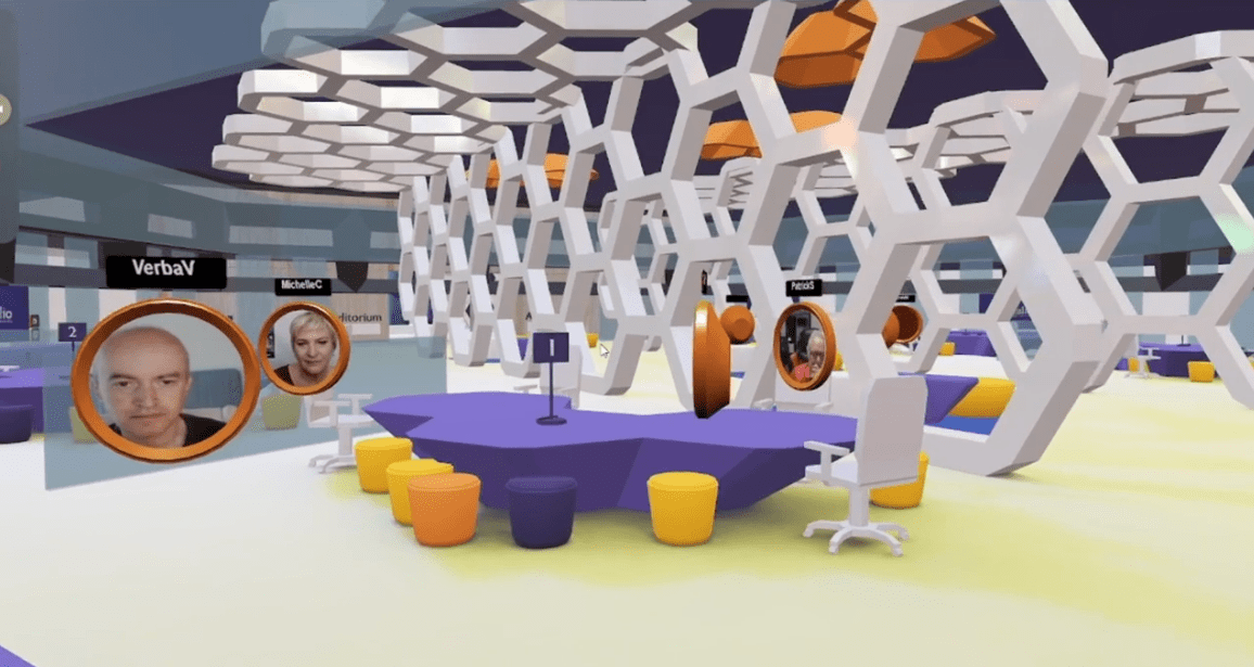 A modern 3D virtual office space with people’s live faces in circular avatars with their names above them, huddled around a shared team desk
