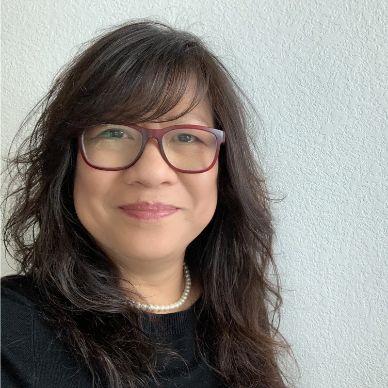 Headshot of Imelda Alejandrino - woman with brown hair wearing red glasses