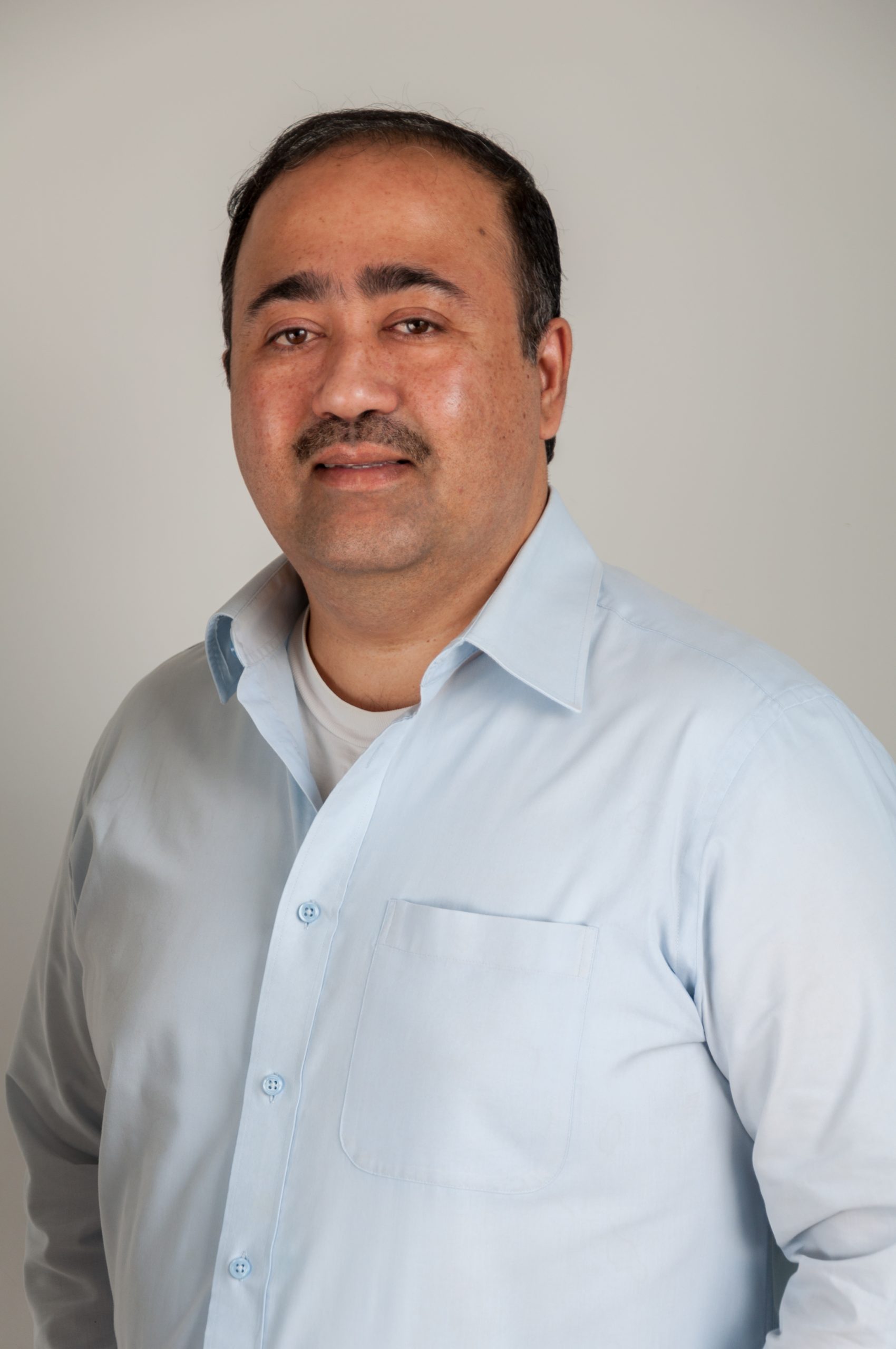 Headshot of Indranil Mukherjee - male with black hair wearing light blue shirt