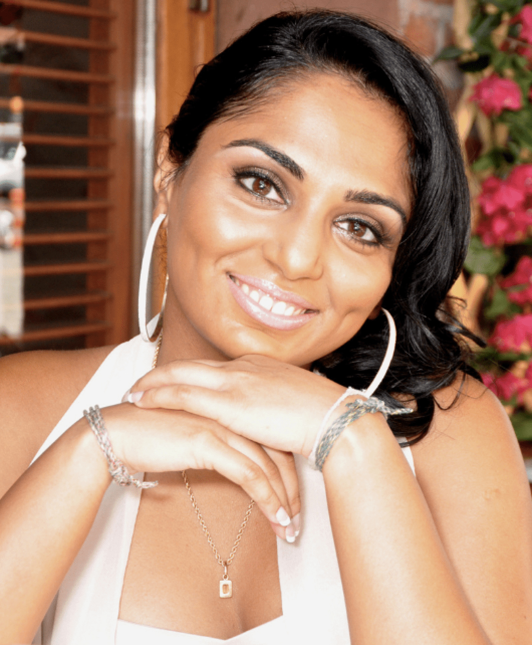 Headshot of Kay Suthar - woman with black hair pulled to side smiling with large earrings