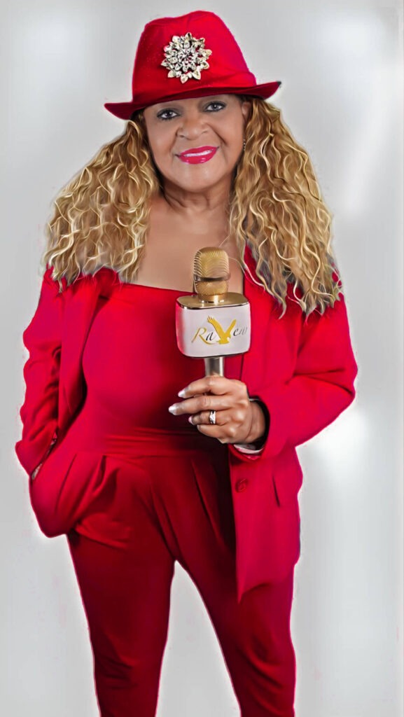picture of raven blair glover holding a microphone and wearing a red suit and hat