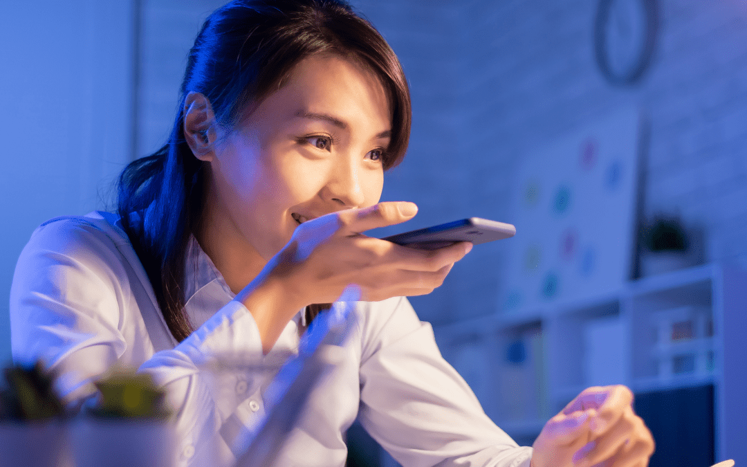1. A woman sitting at a desk, focused on a phone, with papers and a laptop visible in the background.